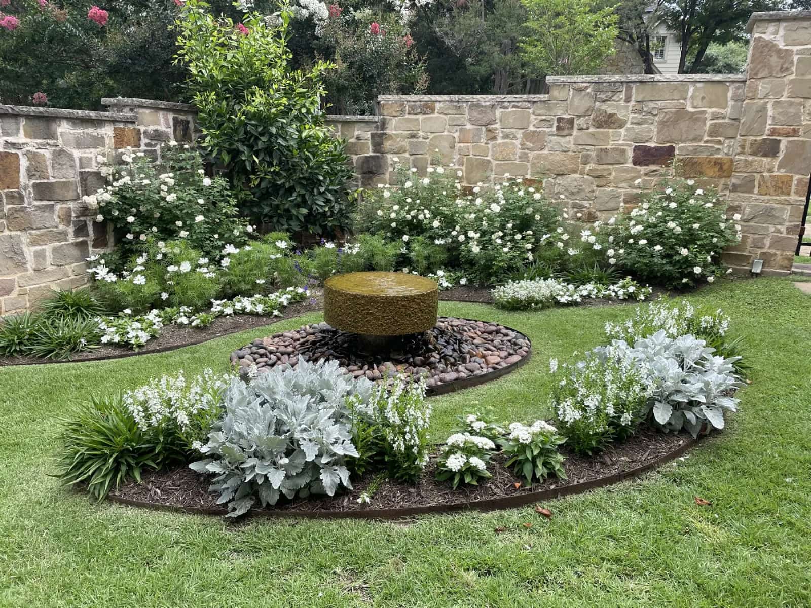 Austin garden with stone wall, white flowers, and layered planting